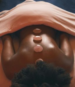 woman lying on her stomach with hot rocks on her back