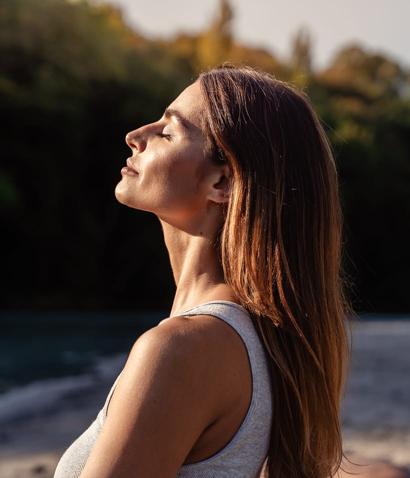 a woman facing the sun with her eyes closed